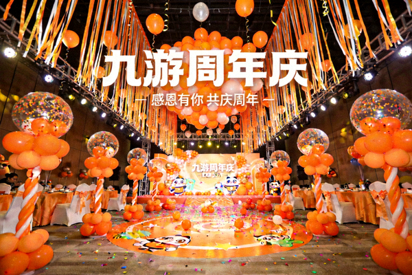 九游周年庆活动新闻配图，展示装饰着橙色气球和彩带的庆祝派对现场